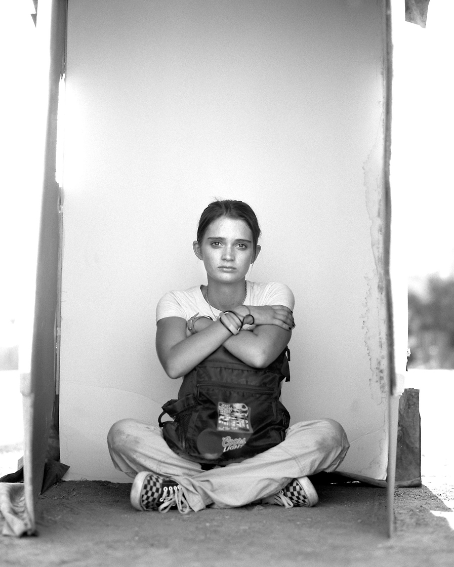 Editorial photography of homeless young woman sits on the ground with her backpack in a portrait box by Phoenix commercial photographer Jason Koster.