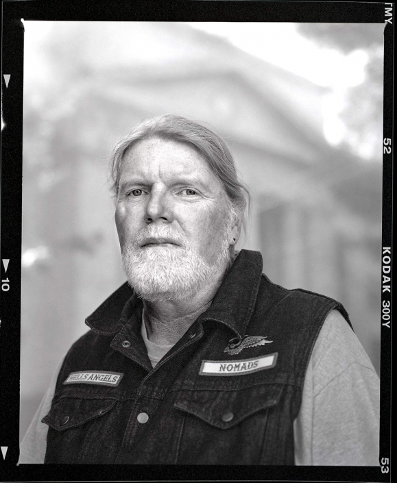 Editorial photography portrait of white bearded motorcycle club member with denim vest outside of Prescott Arizona Courthouse by Phoenix commercial photographer Jason Koster.