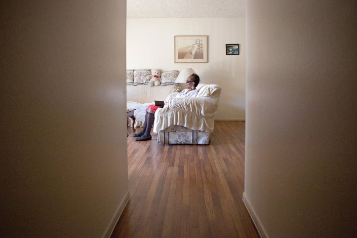 Editorial photography of a visually impaired woman sits on couch at the end of the hall waiting for assistance. Image by Phoenix commercial photographer Jason Koster.