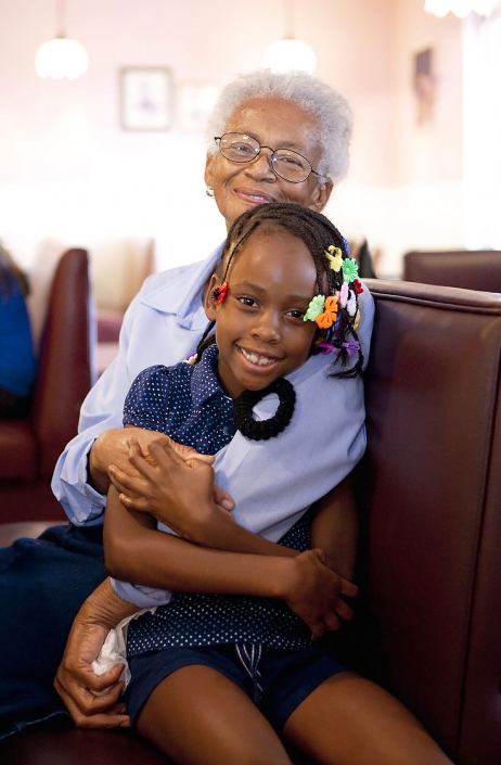 Editorial portrait of smiling grandma hugs smiling granddaughter with barrettes. Image by Phoenix commercial photographer Jason Koster