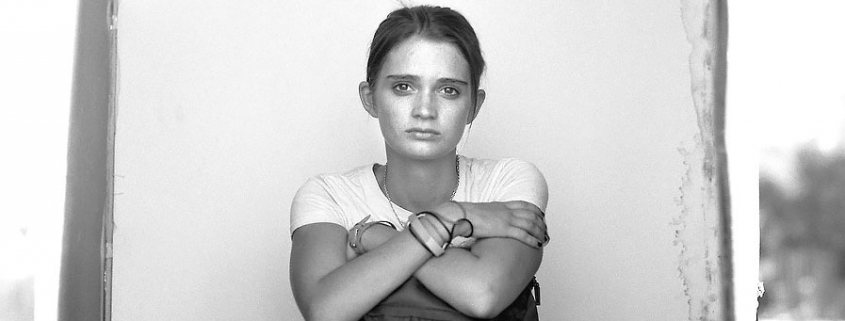 Editorial photography of homeless young woman sits on the ground with her backpack in a portrait box by Phoenix commercial photographer Jason Koster.